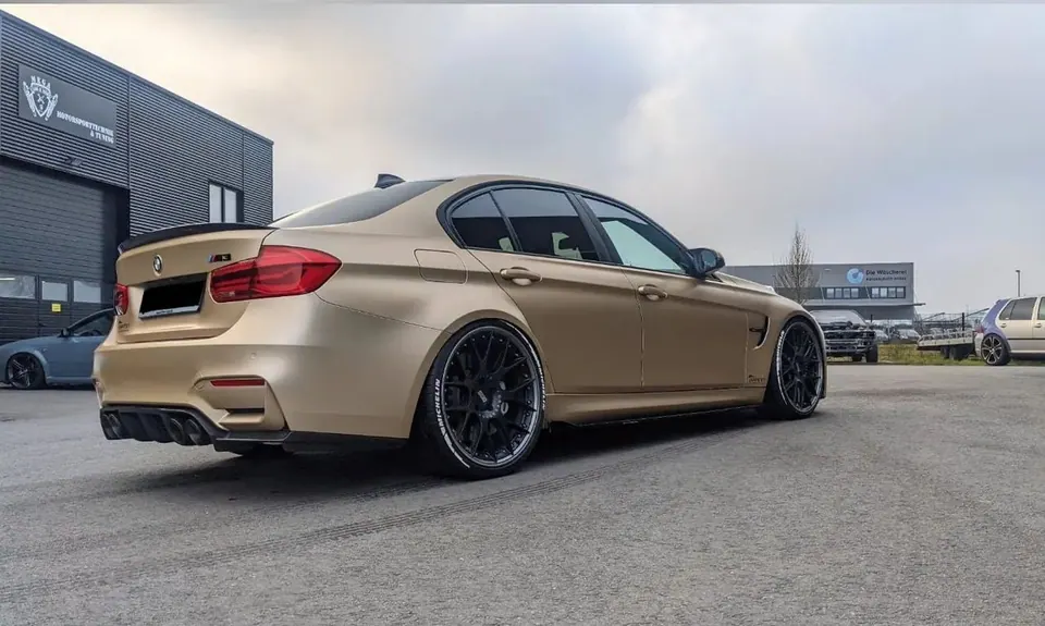 Goldener BMW M3 mit schwarzen Felgen in einer Werkstatt für ein Wertgutachten